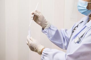 A doctor holding a SARS-CoV-2 test swab.