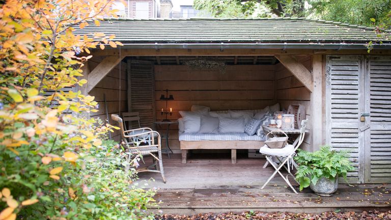 花园棚子在一个木制的室外庭院房间里有木天床和淡蓝色软装饰。