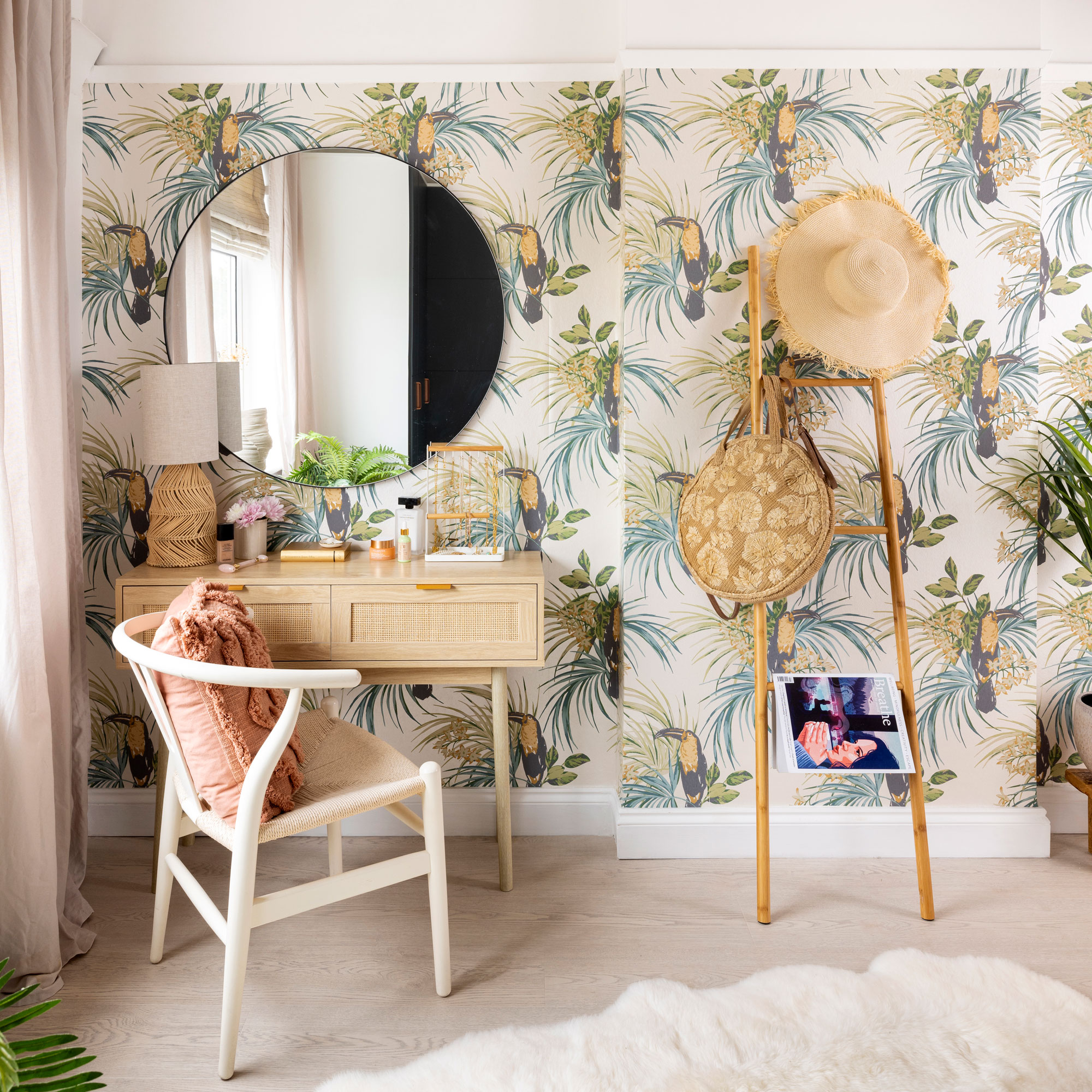 bold botanical wallpaper on wall with circular mirror and dressing table