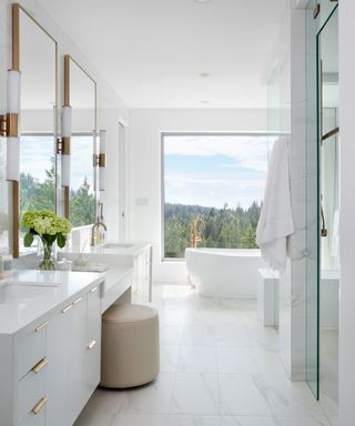 A bathoom with white marble floors, standalone white bathtub and white vanity