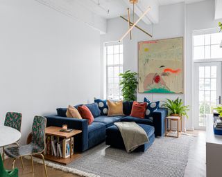 sofa arranging mistakes, white apartment living room/dining space, large artwork, blue sectional, rug, table and chairs