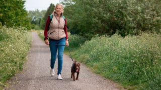 Woman walking with her dog through a woodland area while following the Rosemary Conley diet