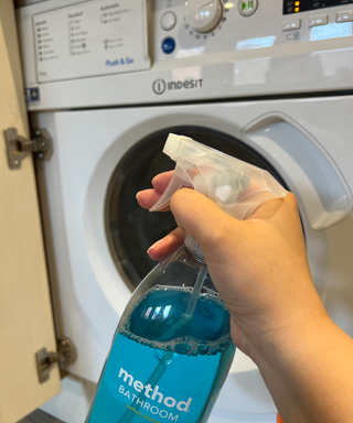 A bottle of method eucalyptus bathroom spray in front of washing machine