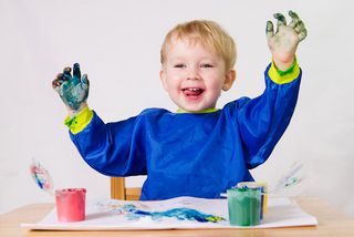 a happy toddler boy finger painting