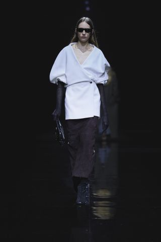 Khaite model wearing a white minidress with leather gloves and a brown pencil skirt.