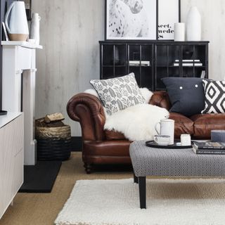 brown leather sofa in cosy living room layered with cushions and blanket