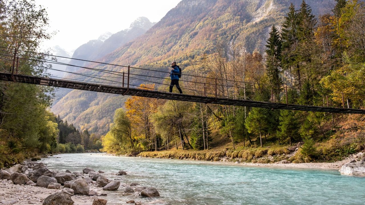 man walks over suspension bridge near Julian Alps