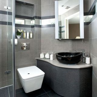 bathroom with grey tiles wall and mirror and washbasin and toilet