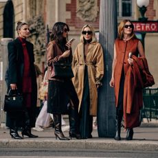 four women standing on the street at paris fashion week in trendy fall clothing