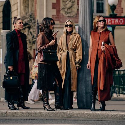 four women standing on the street at paris fashion week in trendy fall clothing