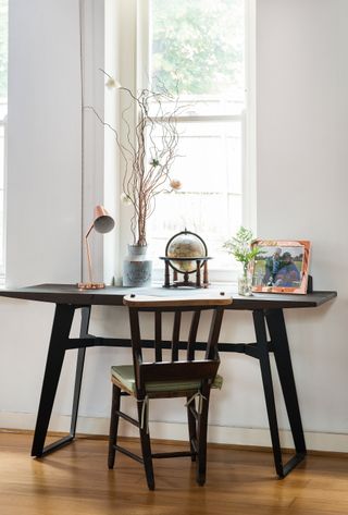 black desk i a white room with wooden flooring