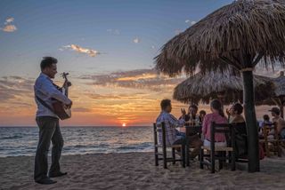 A guitar player serenades diners on a beach in Puerto Vallarta, Mexico, at sunset