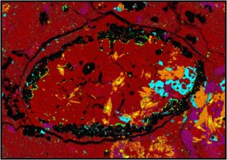 This false-color microscope image of a meteorite sample collected in Sudan shows amphibole crystals, a unique feature, highlighted in orange.