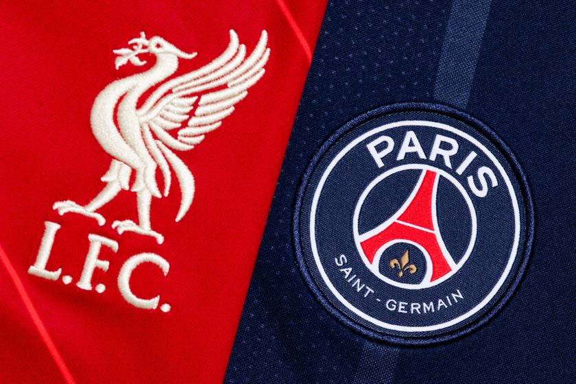 A close-up showing the Liverpool crest on a red shirt and the PSG crest on a dark blue shirt