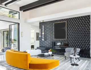 A living room with a yellow curving soda and a black and white armchair