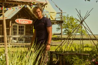 Rudy Pankow as JJ, standing in front of a beachside shack, in 'Outer Banks' season 4.