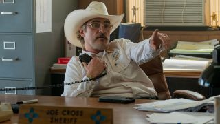 Joaquin Phoenix as Joe Cross at a desk in Eddington