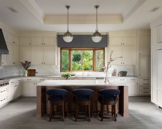 Kitchen with cream cabinets and large central island with three bar stools