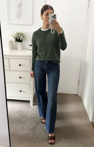 Woman in olive green sweater and jeans.