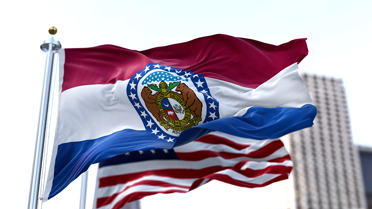 Flag of Missouri flying on a cloudy day with the US flag flying behind it