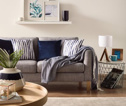 Grey textured sofa draped with deep blue and striped cushions