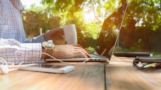 A businessman working remotely outdoors in sunny conditions