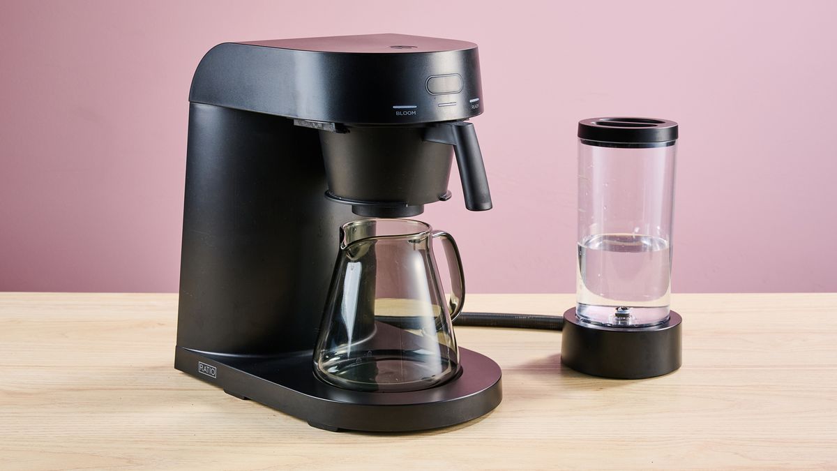 The Ratio Four, carafe and water tank on a desk in front of a pink background.