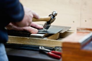 An artisan hammers the leather corners of a Globe-Trotter classic suitcase