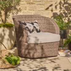 Next's Natural Alvor Swivel Chair on a patio with potted plants