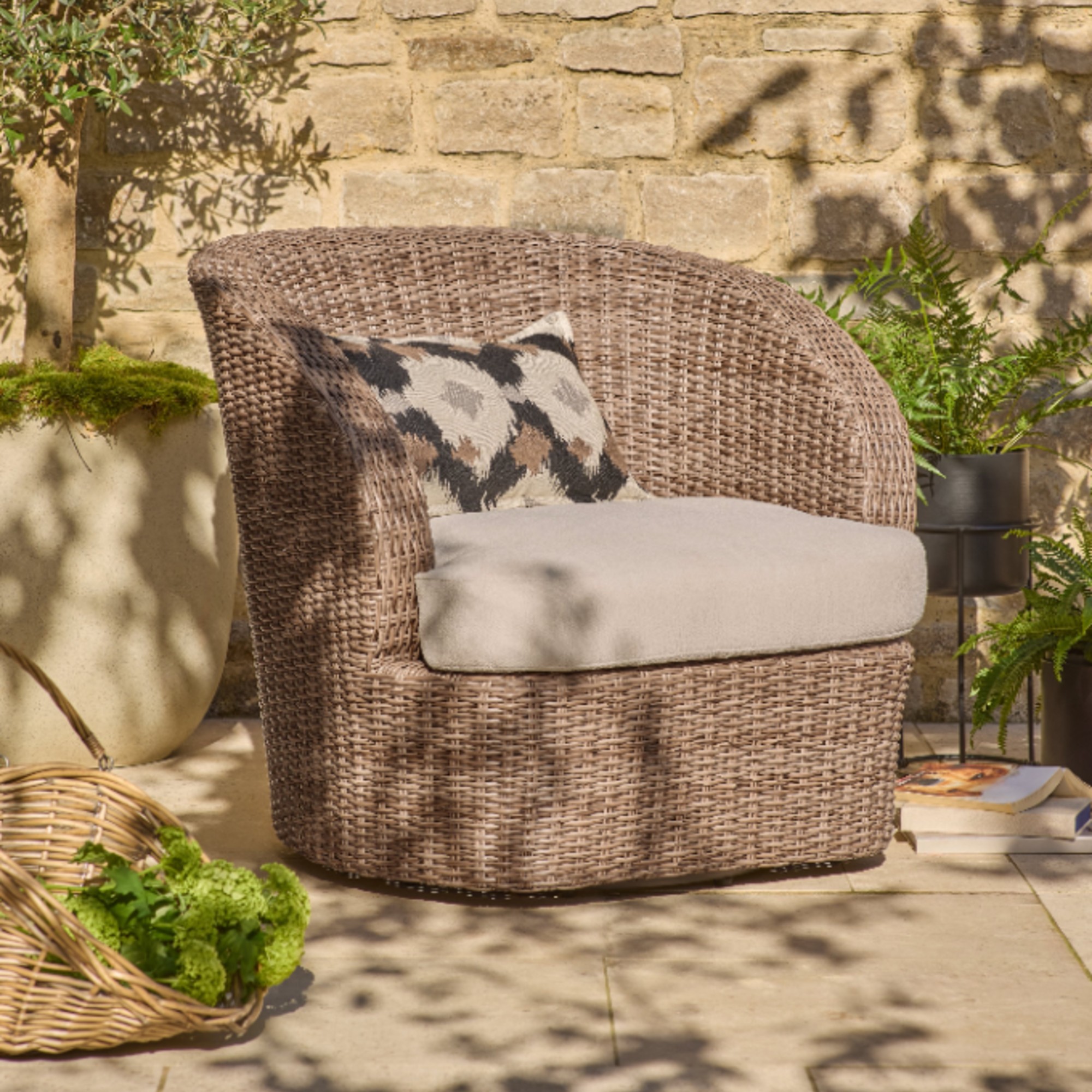 Next's Natural Alvor Swivel Chair on a patio with potted plants