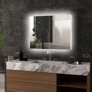 A bathroom with dark grey wall tiles, a light up mirror cabinet and a large marble topped bathroom vanity