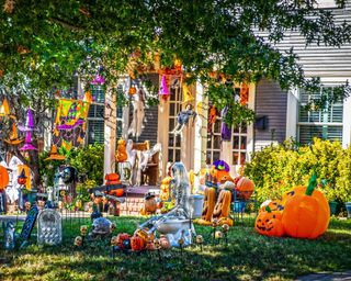 House with yard filled with Halloween decorations of every kind including skeleton on toilet seat and many tombstones