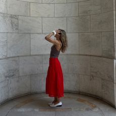 Eliza Huber wearing a red midi skirt, tan camisole, white loafers, and white scrunchie from the J.Crew x Maryam Nassir Zadeh collaboration.