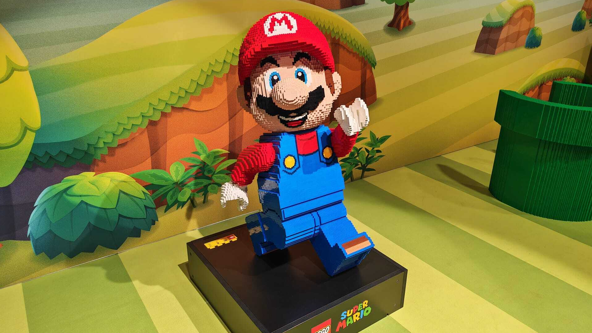 A life-size Lego Super Mario figure against a backdrop of the Mushroom Kingdom