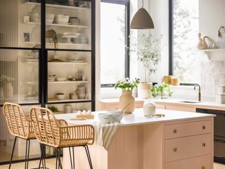 pink kitchen with kitchen island/breakfast bar, ceiling light, pantry, wicker bar stools