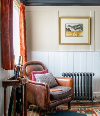 A corner of a country living room with wall panelling and a leather armchair
