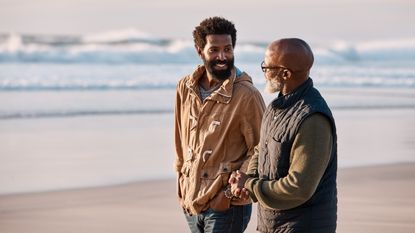 A son and father walk on the beach.