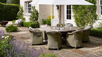 传统花园中带有桌椅和白色阳伞的露台铺装理念