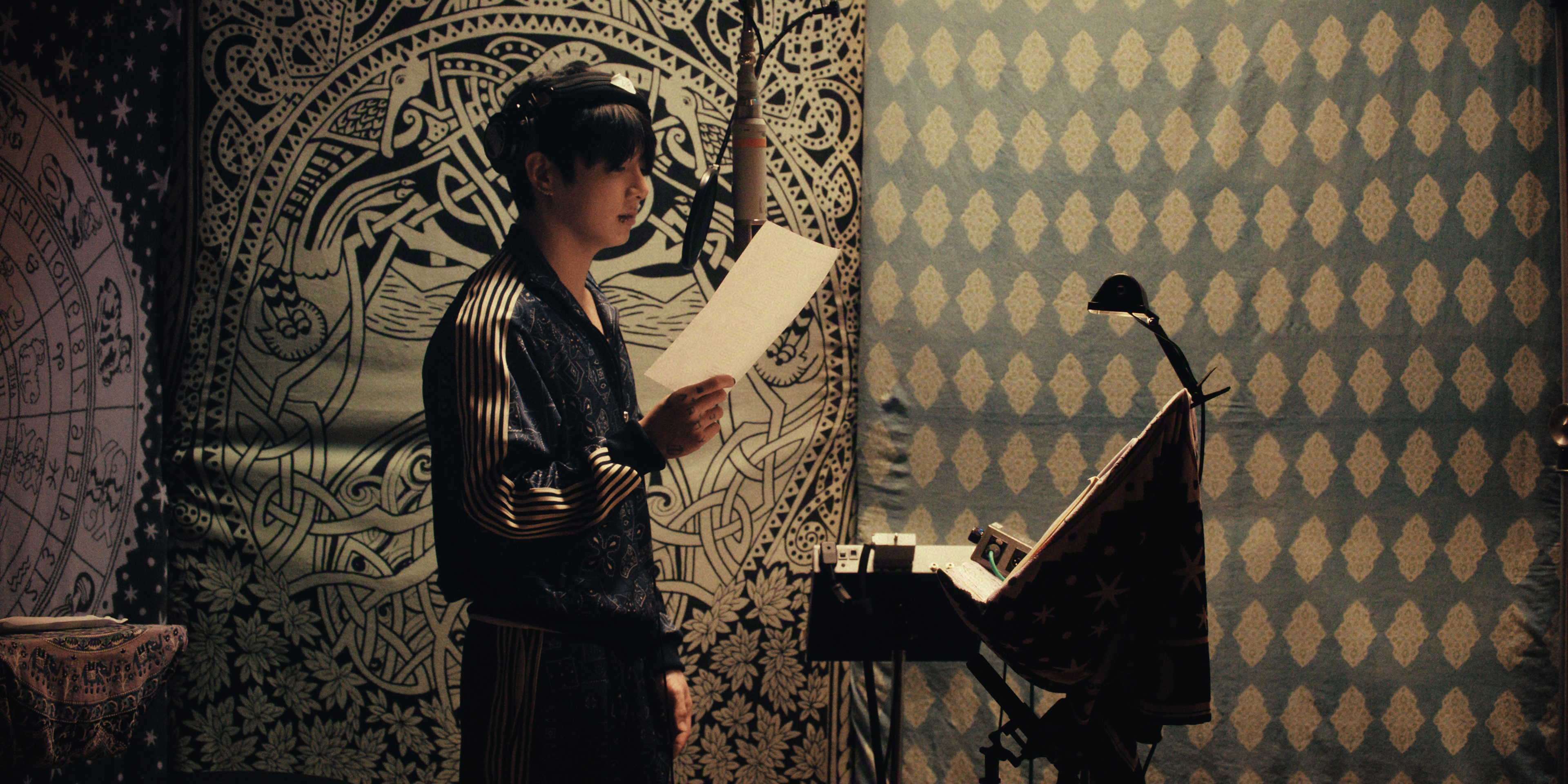 BTS member Jung Kook records in a studio with tapestry-lined walls, in the Netflix documentary 'BTS: THE RETURN.'
