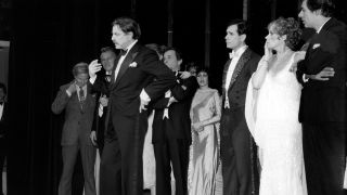 American stage and television actor Jerry Orbach (1935 - 2004) (right) and the cast of the Broadway musical 42nd Street looking on as the show's producer David Merrick (1911 - 2000) (center), at the curtain call, announces that the show's director, Gower Champion, had died of a rare blood disease some hours earlier.