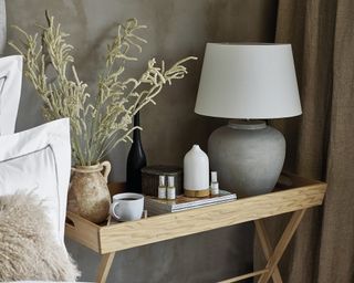 An electronic diffuser in neutrally-decorated bedroom on wooden bedside table by The White Company