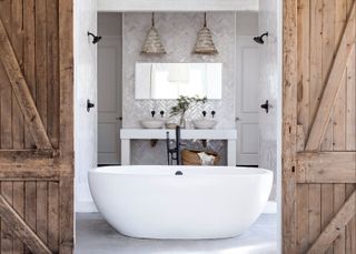 Farmhouse bathroom with white tub, woven ceiling lamps and barn door entrance