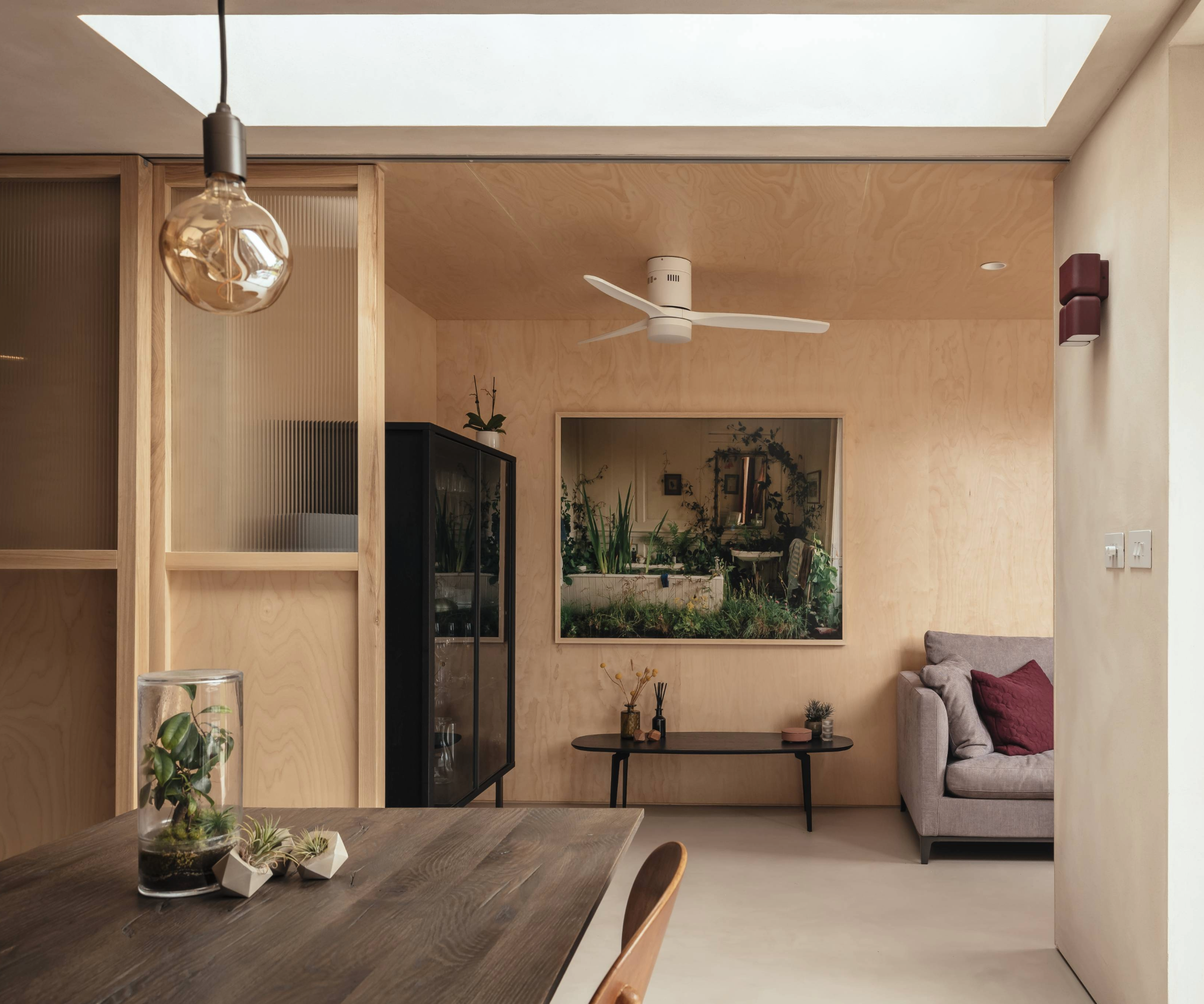 Open plan diner and living area with roof light and plywood walls