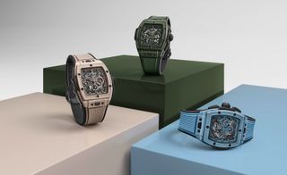 three watches on plinths, in beige, green and blue