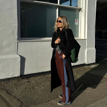 Fashion influencer @lucywilliams02 wearing an on-trend winter outfit in London with sporty burgundy Adidas pants.