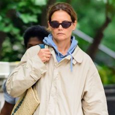 Katie Holmes wears a khaki trench coat and a blue hoodie while walking in New York City