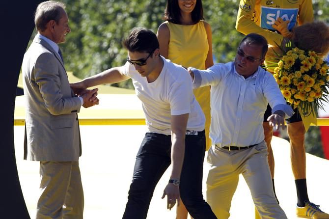 Bernard Hinault is both host and bouncer for the Tour de France podium, here he tosses an infiltrator from the dais in 2012.