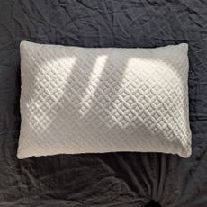 The Aeyla Adjustable FOAMO Pillow being tested on a bed with a grey linen duvet cover