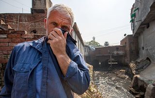 Jeremy Wade covers his nose against the acrid smell of pollution pouring into the River Ganges from tanneries in the industrial city of Kanpur, India