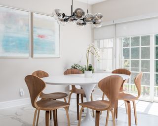 Light and breezy family dining room with white oval table, curved wood chairs, and large serene artwork on wall.